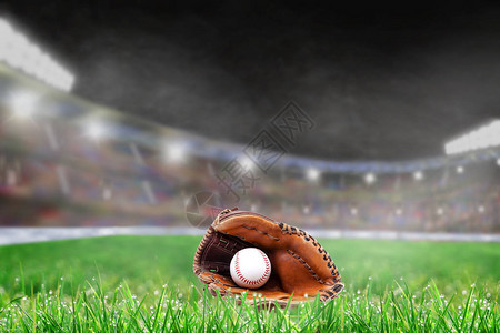 棒球手套和球在明亮的室外体育场的草地上图片