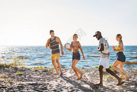 带着球和背包一起在沙滩上行走的快乐年轻人图片