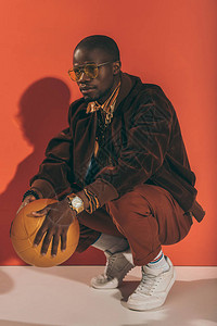 时尚的非裔美国人跪着拿金篮球图片
