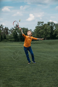 白种男孩在绿地上玩羽毛球用花冠和穿梭图片
