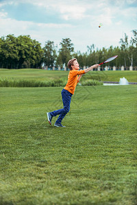 白种男孩在绿地上玩羽毛球用花冠和穿梭背景图片