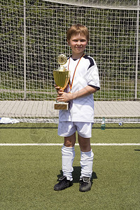 身着足球服的年轻男孩为杯子感到骄傲他的足球队在锦标赛中赢背景图片
