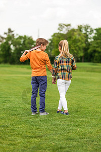 男女站在绿地上时手牵男孩在肩膀上拿图片