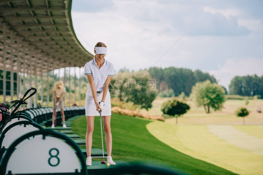 高尔夫球场上带高尔夫球杆的微笑女高尔夫球手图片