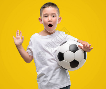 一头黑发的小孩在玩足球时惊恐地惊讶地脸色惊恐图片