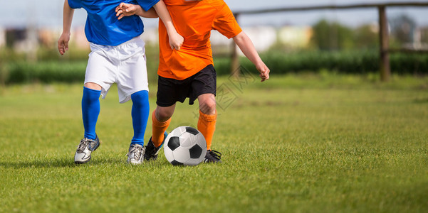年轻男孩玩足球比赛穿着蓝色和橙色制服图片