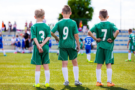 年轻的足球队预备队球员站在一起观看青年队的足球锦标赛比背景图片