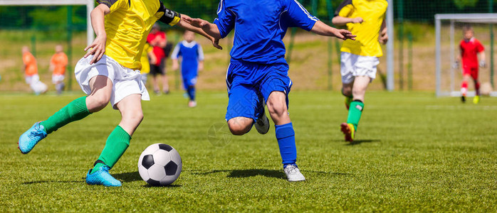 足球运动员在运动场上跑步和踢球年轻男孩在球场上踢足球比赛青少图片