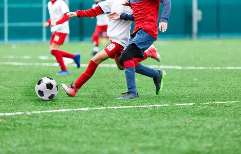 穿着和白色服的男孩在绿草场上踢足球青少年足球比赛儿童体育比赛图片