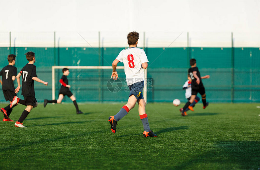 穿着白色黑运动服的男孩在足球场上奔跑年轻的足球运动员在比赛中运球和踢足球训练积极生活方式运动图片