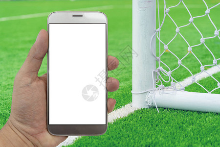 手拿着有足球场背景的智能手机图片