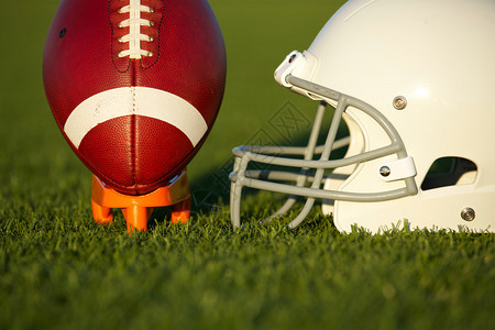 美式足球和头盔在球场上开球背景图片