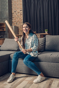 在客厅沙发上坐着棒球的年轻女子图片