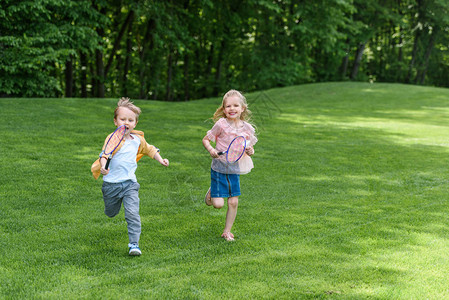 带着羽毛球拍打的可爱笑孩子在公园图片
