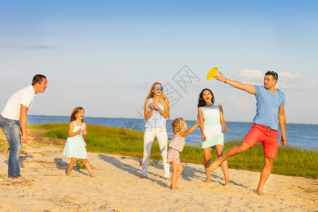 朋友和孩子们在海滩上玩飞盘游戏的朋友暑假和家庭概念图片