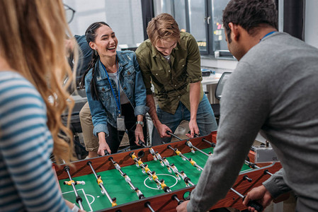 在现代办公室玩桌足球的多文化幸福人民图片