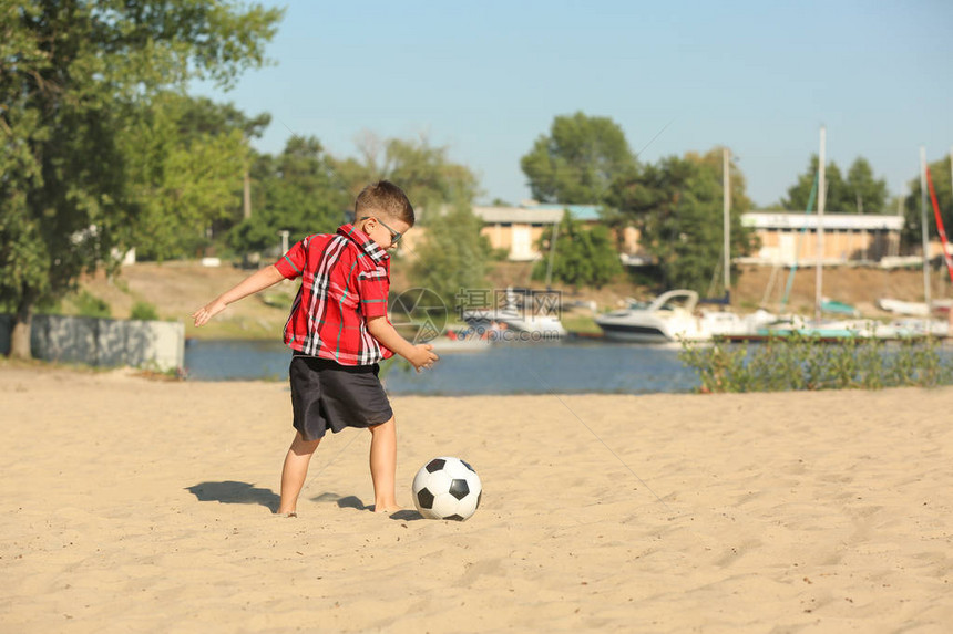 在沙滩上踢足球的小男孩图片