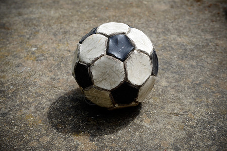 水泥运动场上的旧足球和用过的足球图片