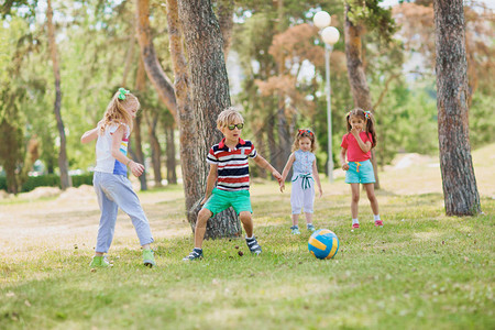 小孩子在公园绿草坪上踢足球图片