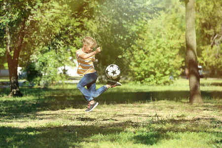 可爱的小男孩在公园踢足球图片
