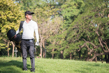 亚洲年轻男高尔夫球手在高尔夫球场上带着高尔夫图片