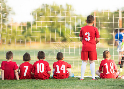 球门后一点儿童足球选手坐在球后观看足背景