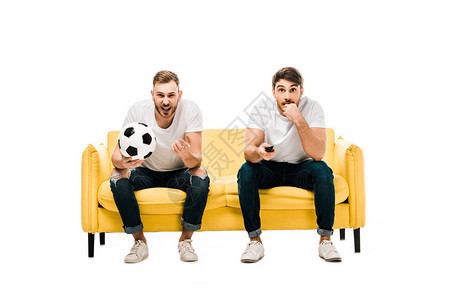 带着足球坐在沙发上观看体育赛事的年轻男子情绪激动图片