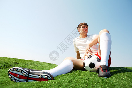 足球运动员坐在绿色草地图片