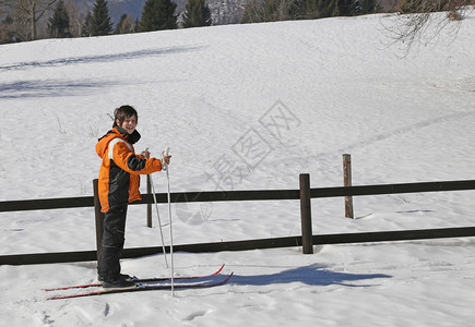 年轻漂亮男孩在冬天在山上的白雪上滑图片