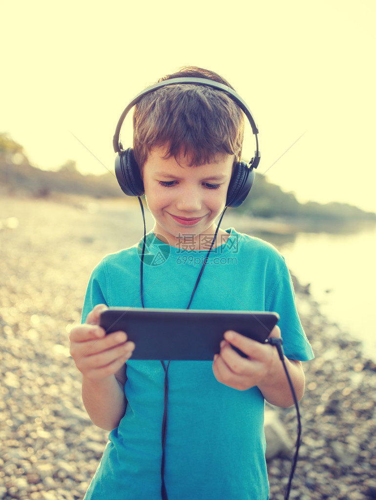 快乐的小男孩玩平板乐听音乐或看视频图片