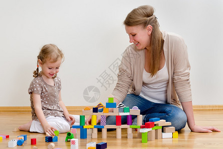 坐在地板上玩砖块的可爱小女孩和年轻女孩图片