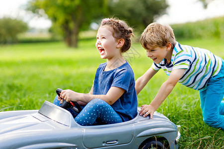 两个健康快乐的孩子在夏日花园里玩大旧玩具车图片