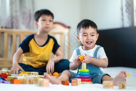 兄弟和一个微笑男孩在床上玩具图片