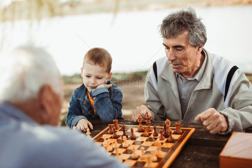 退休老年男子在公园玩乐和下棋与小孙子共图片