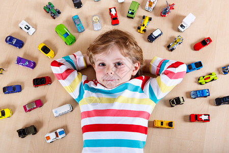 小金发孩子在室内玩具车男孩穿多彩的衬衫图片