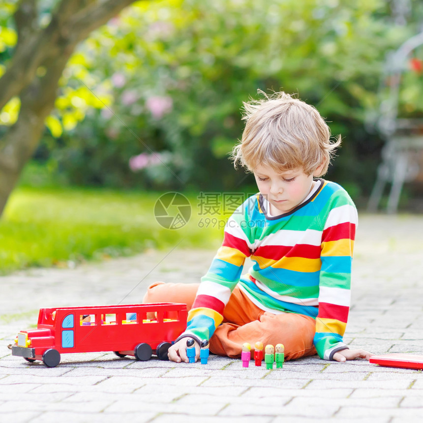 可爱的4岁男孩在夏令营玩木制红校车和玩具图片
