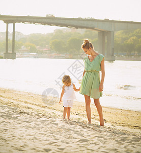 母亲带着学步的儿童开心的在沙滩图片