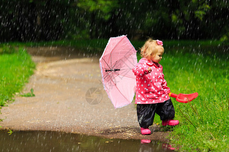 穿着雨衣和野外靴子带雨伞的可爱小女孩图片