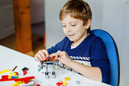 金发小孩玩很多五颜六色的塑料块可爱的学童男孩在建造和创造机器人时很开心创造休闲现代背景图片