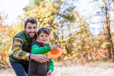 微笑的父亲和可爱的小儿子在秋天公园玩飞图片