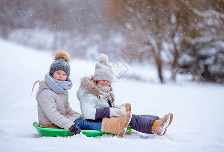 可爱的小姑娘们在雪地上滑雪和户外玩雪图片