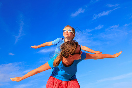 母亲和小儿子在夏日蔚蓝的天空上玩飞机图片