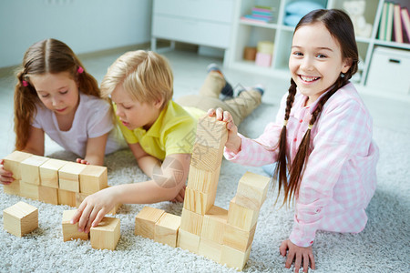 三个小朋友玩木砖一个快乐的女孩看着图片