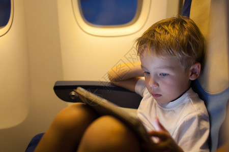 坐在飞机上玩触摸垫的男孩子坐飞机图片