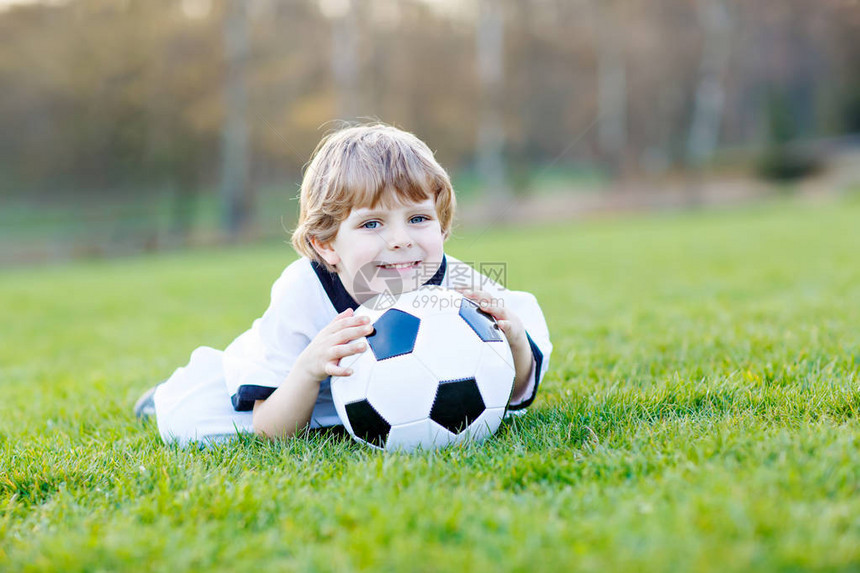 岁的小可爱男孩在球场上踢足球图片