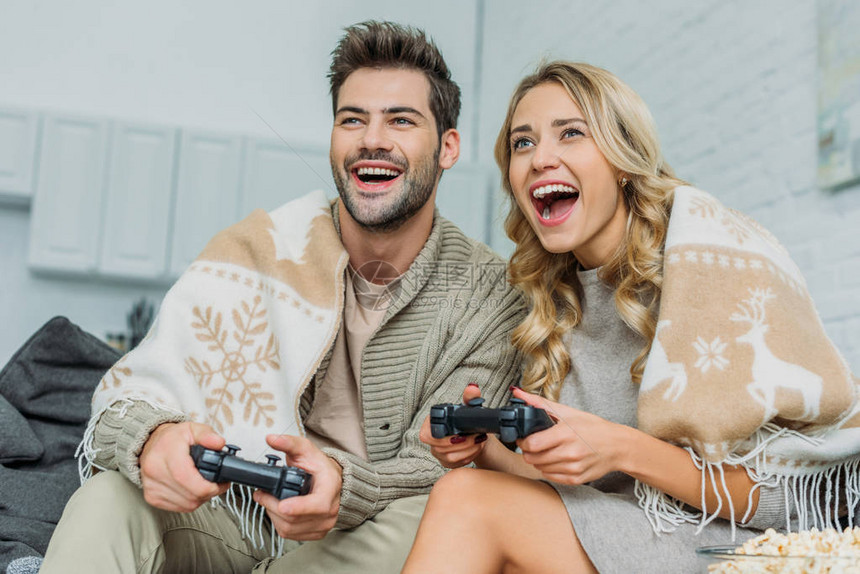 美丽的年轻夫妇玩电子游戏和在家沙发上玩图片