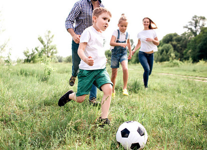 一家人一起踢球的照片男孩跑在大家面前有男人在他身后跑图片