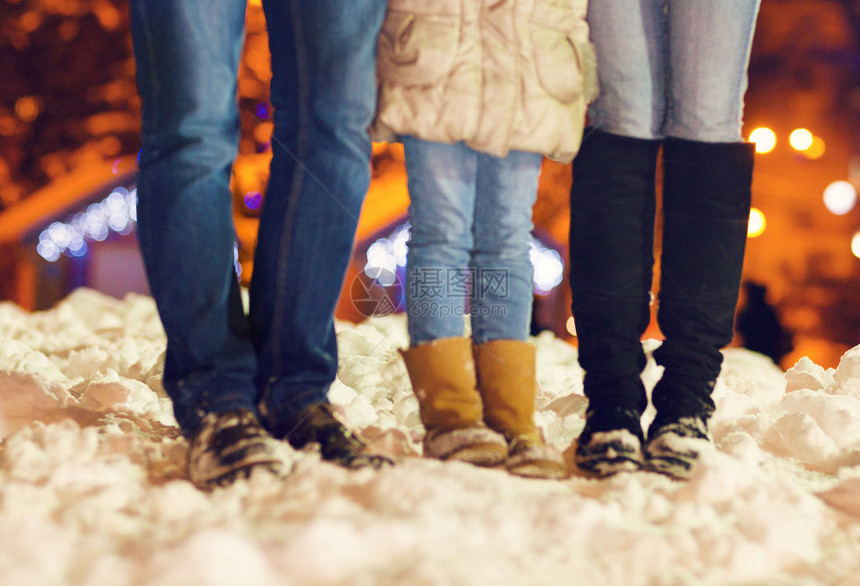 家庭成员在圣诞节灯光下雪上穿冬鞋图片