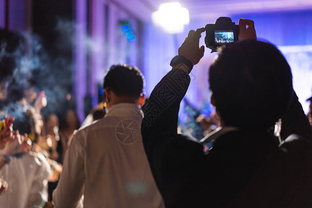 年轻摄影记者拍摄室内晚间庆祝活动照片图片