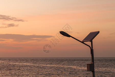 日落时带太阳能电池板的路灯靠海图片